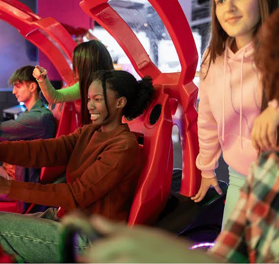 kids-having-fun-at-arcade-with-girl-driving-arcade-game